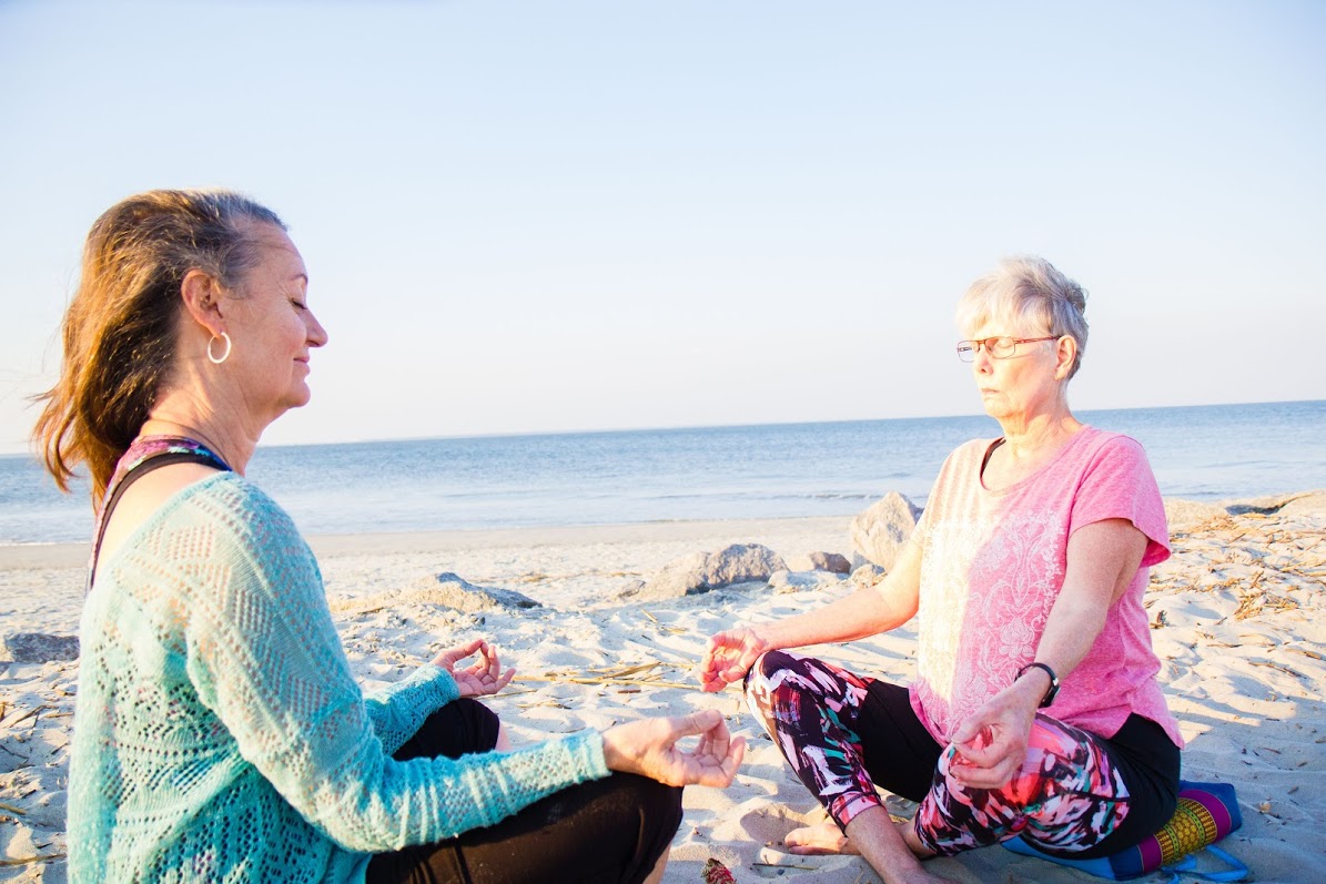 Two women meditating on beach